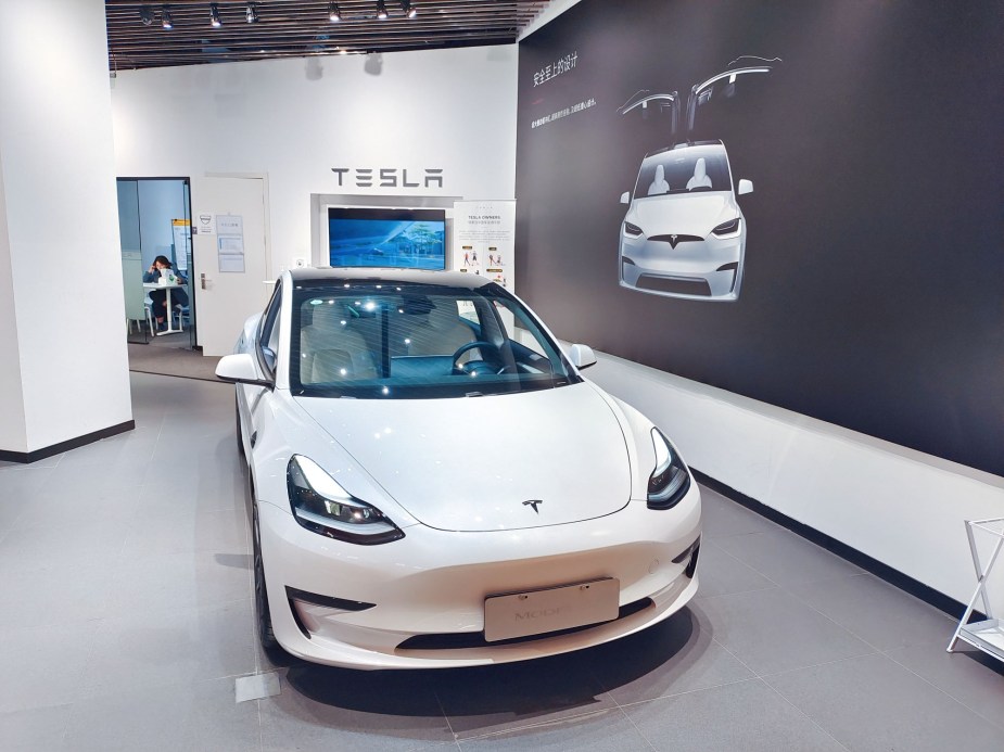 A white Tesla Model 3, which is an EVs With the Longest Range, parked indoors. 