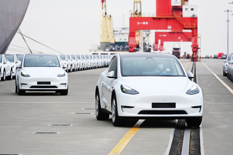 A long line of 2022 Tesla Model Y cars outdoors.