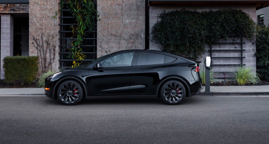 A black 2022 Tesla Model Y electric SUV is parked and charging.