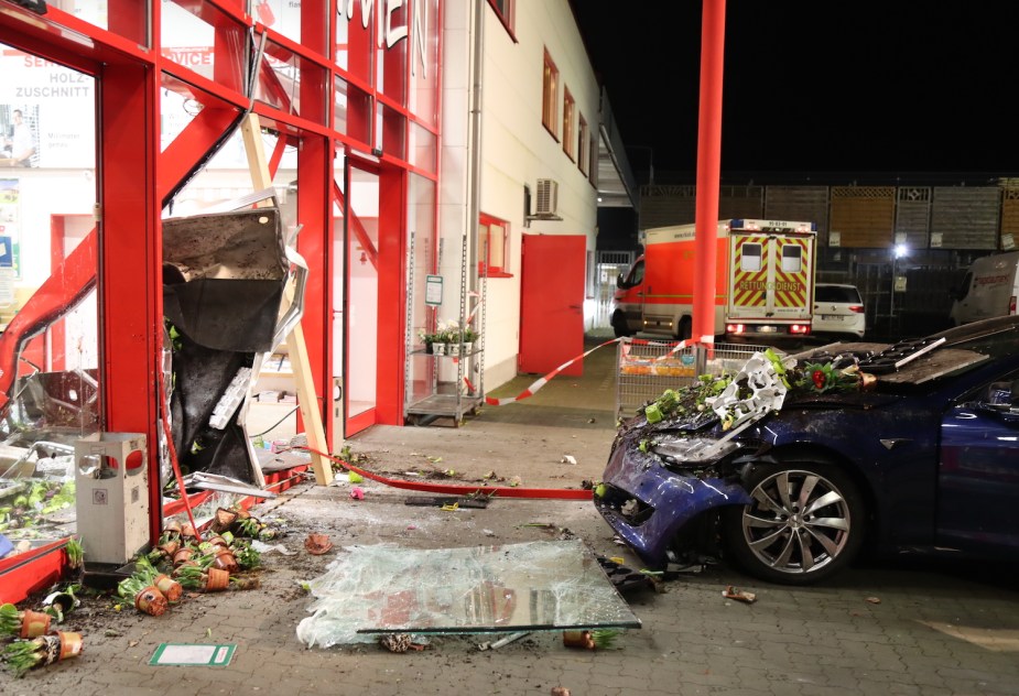 A blue Tesla sedan, its grille smashed in after striking a hardware store.
