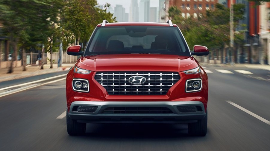 A red 2022 Hyundai Venue subcompact SUV is driving on the road.