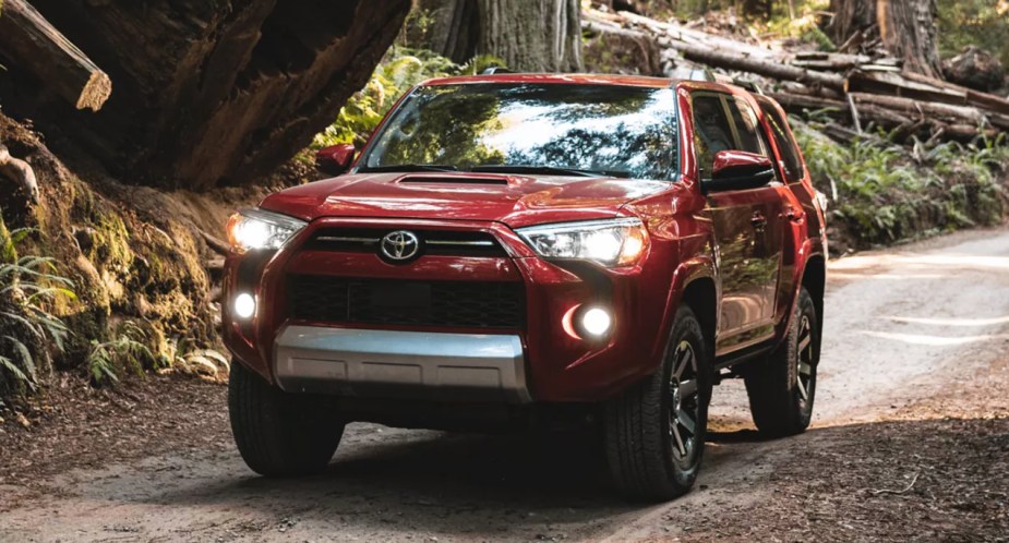 A red 2022 Toyota 4Runner midsize SUV is driving off-road.