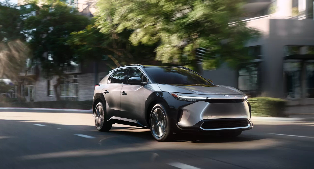 A gray 2023 Toyota bZ4X electric SUV is dirivng on the road.