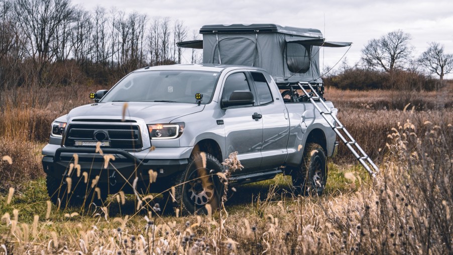 This truck is set up for camping with a tent and a ladder