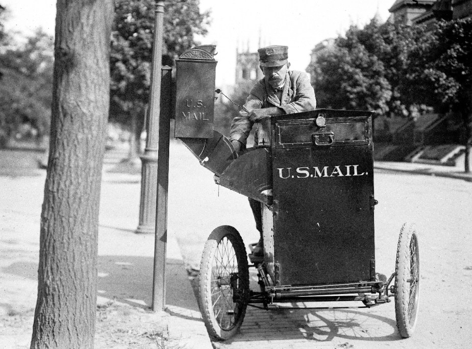 A mail carrier delivering mail on an old USPS bicycle