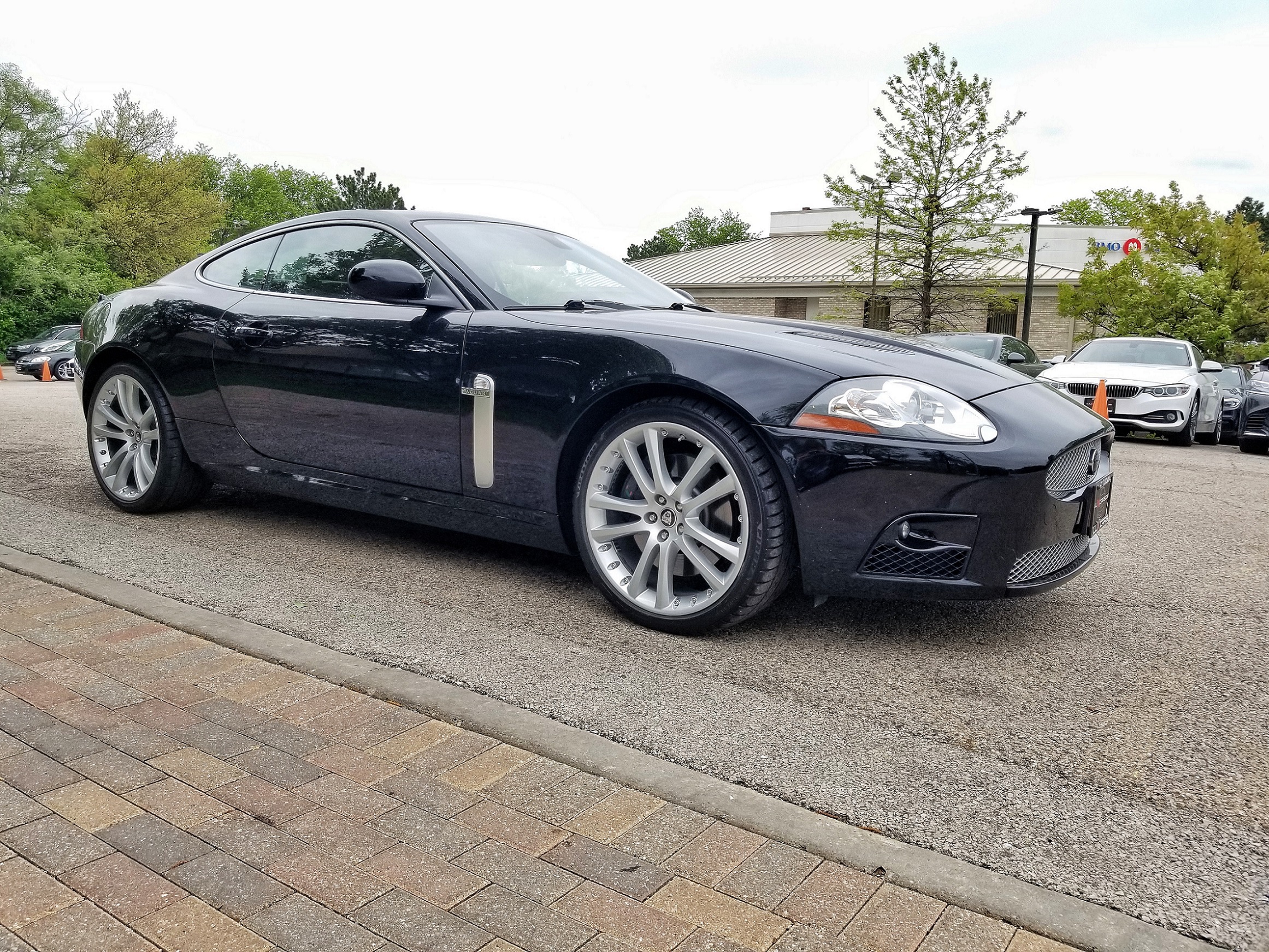 A black used 2007 Jaguar XKR Coupe in a used car dealership parking lot about to head to a pre-purchase inspection