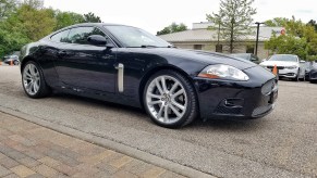 A black used 2007 Jaguar XKR Coupe in a used car dealership parking lot about to head to a pre-purchase inspection