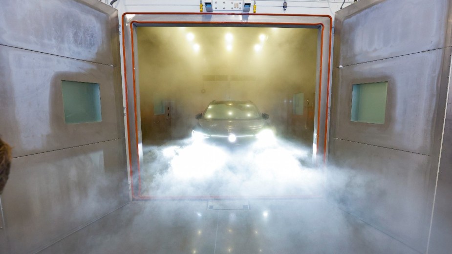 an electric volkswagen has its lights shine through the dust from the climate chamber after abrasive battery testing