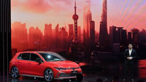 A red Volkswagen Golf GTI a sports car in front of a skyline background indoors.