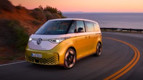 A green and white 2024 Volkswagen ID.Buzz electric minibus is driving on the road.