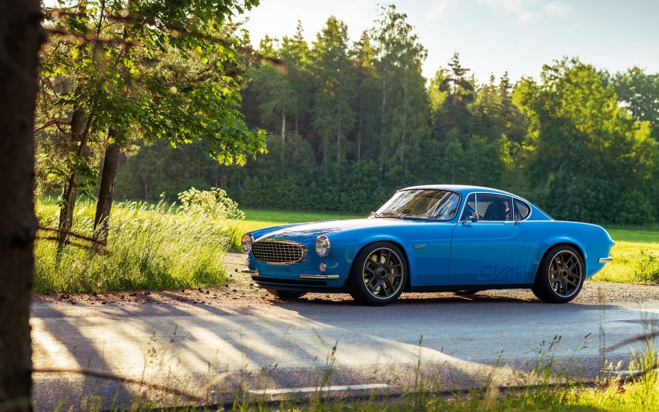 A blue Volvo P1800 Cyan parked on a forestside road