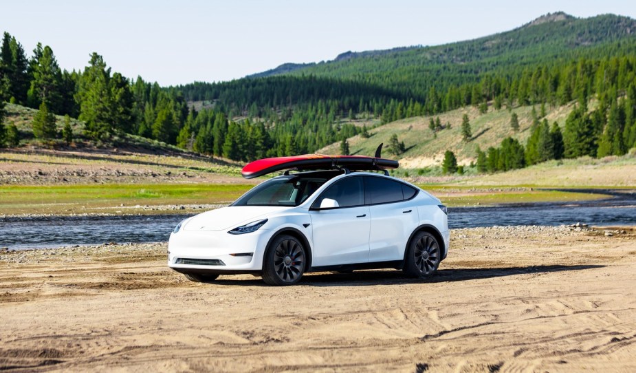 White 2023 Telsa Model Y with a surfboard, highlighting its release date and price