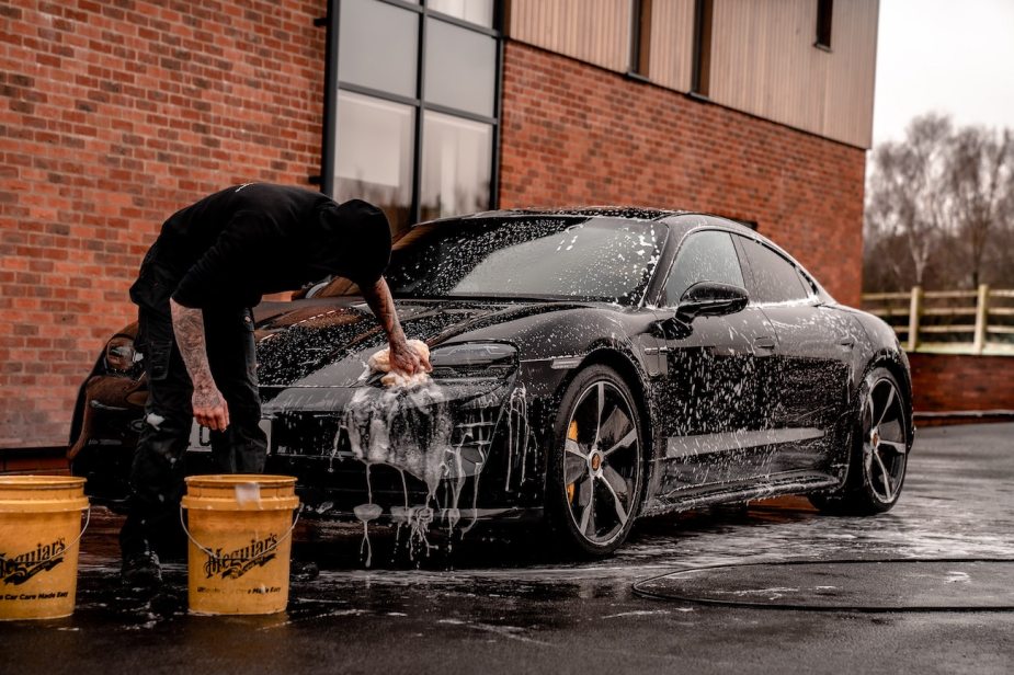 A man washing his car using the two-bucket method