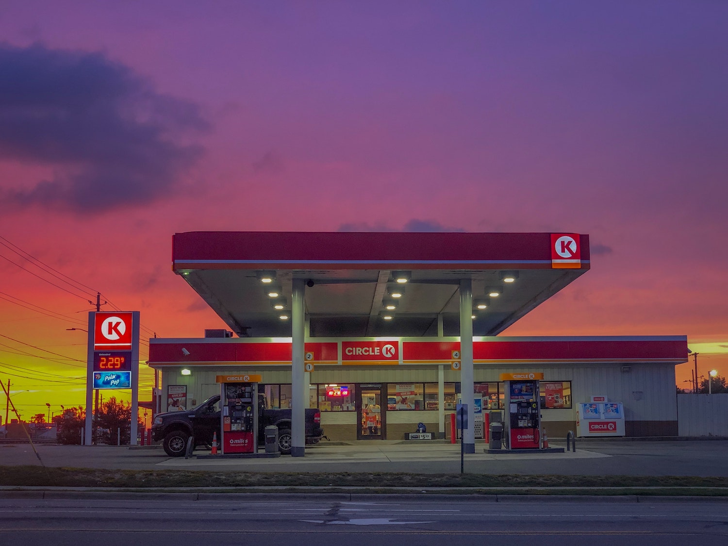 The sunrising over a gas station and convenience store on a deserted highway.