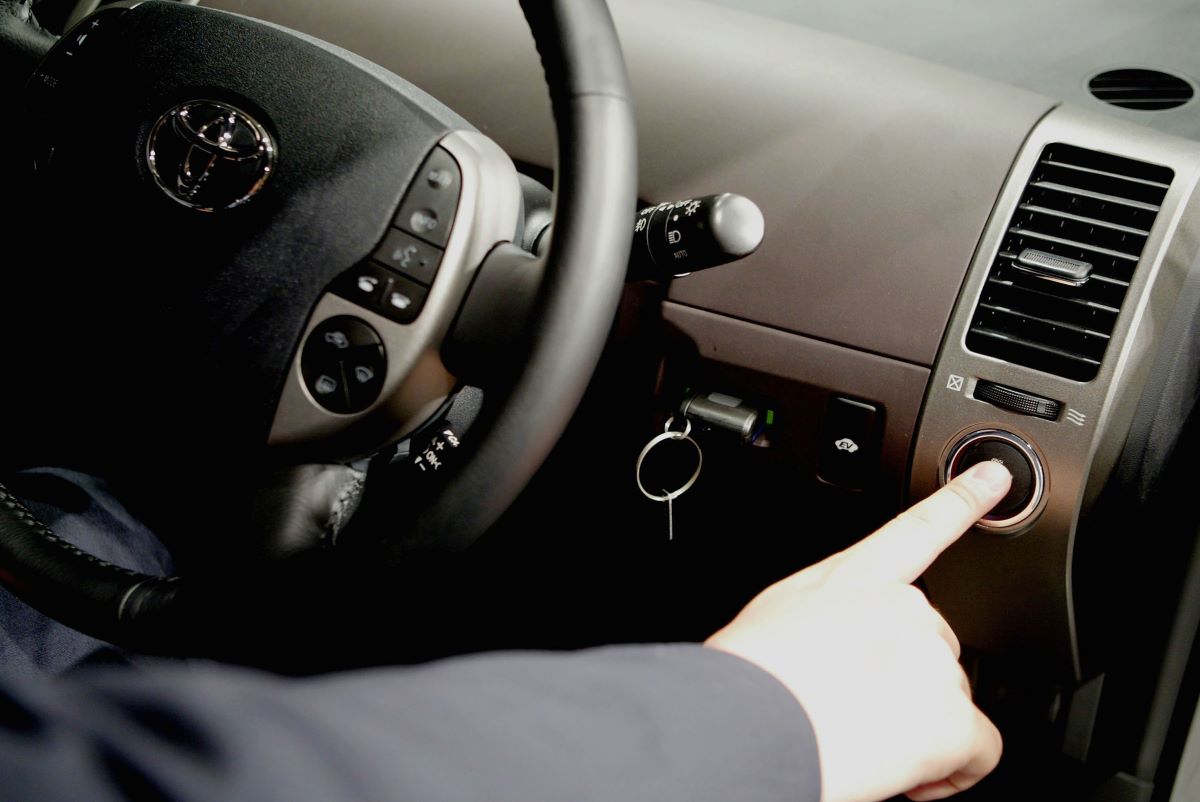 A hand presses the push-button start on a keyless ignition in a car