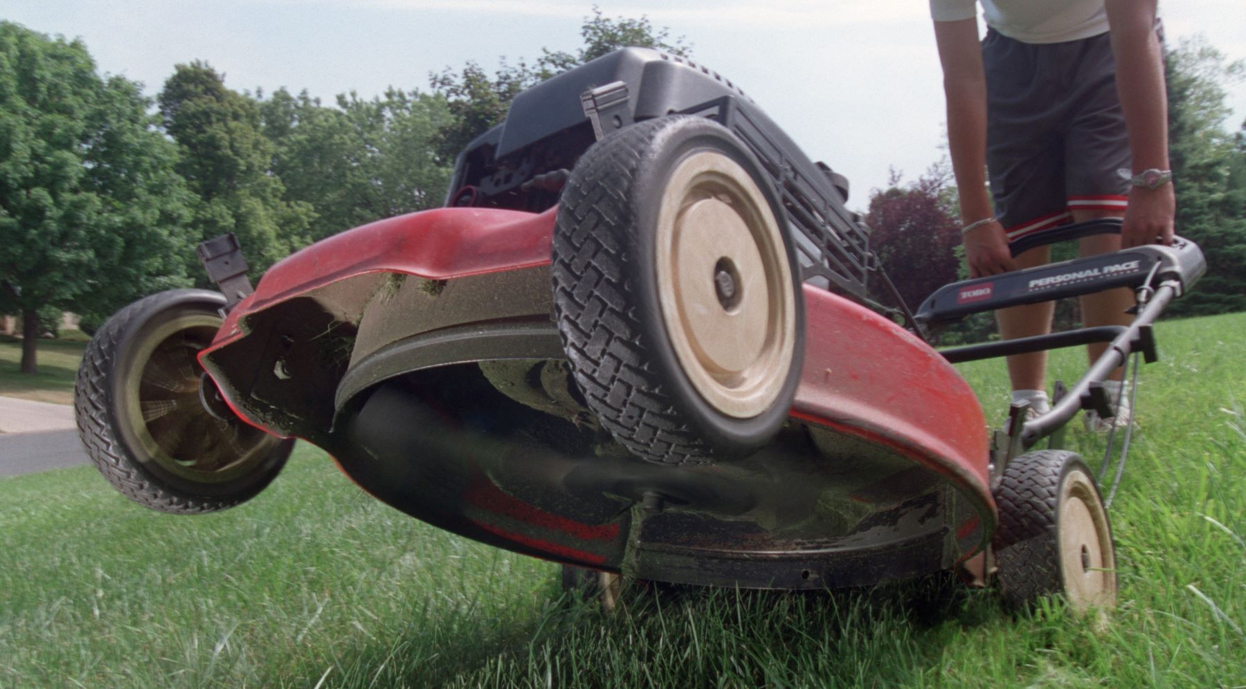 A tilted back lawn mower showing the dangerous spinning blade, which causes many safety accidents