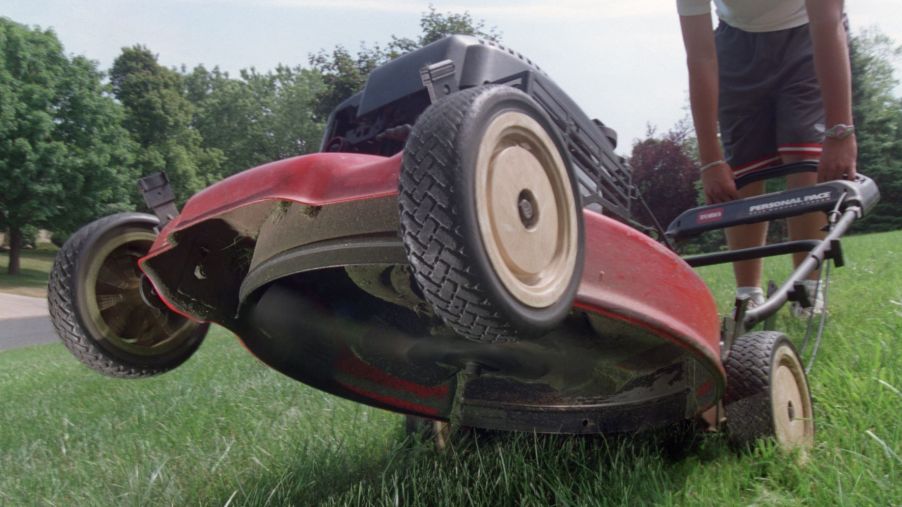 A tilted back lawn mower showing the dangerous spinning blade, which causes many safety accidents