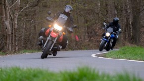 Two people riding a motorcycle in a curve on a country road.