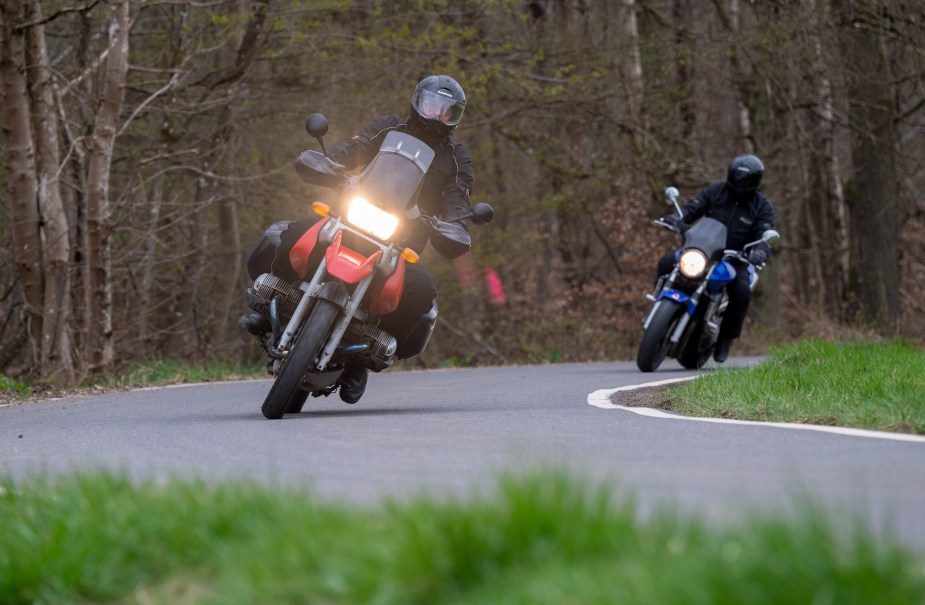 Two people riding a motorcycle in a curve on a country road.
