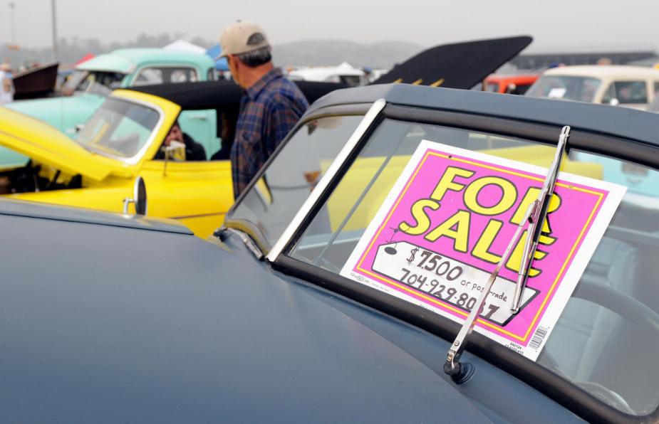 A "for sale" sign is seen on an old classic car.