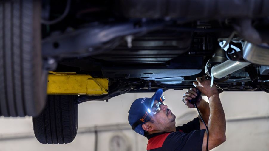 A technician marking a catalytic converter with license plate numbers to prevent theft in Huntington Beach, California