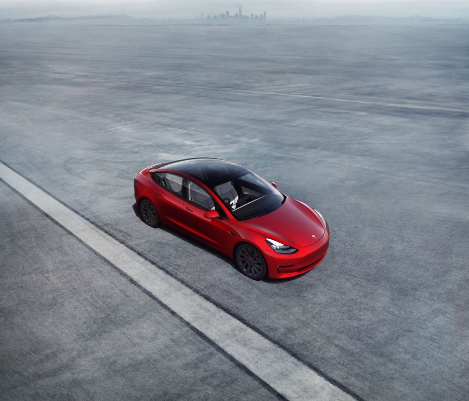 Red Tesla Model 3 parked in a parking lot