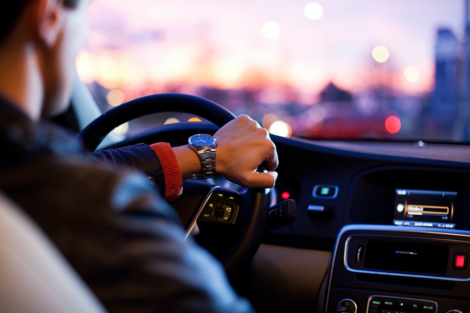 A driver rests his hand on the steering wheel.