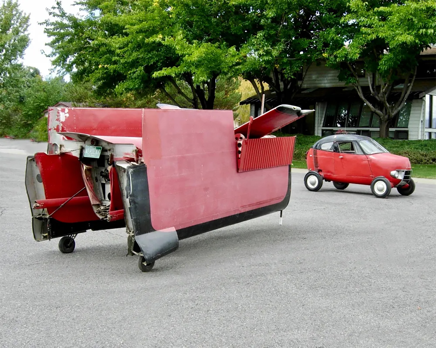 Red 1956 Taylor Aerocar flying car parked on street with its wing and fuselage trailer
