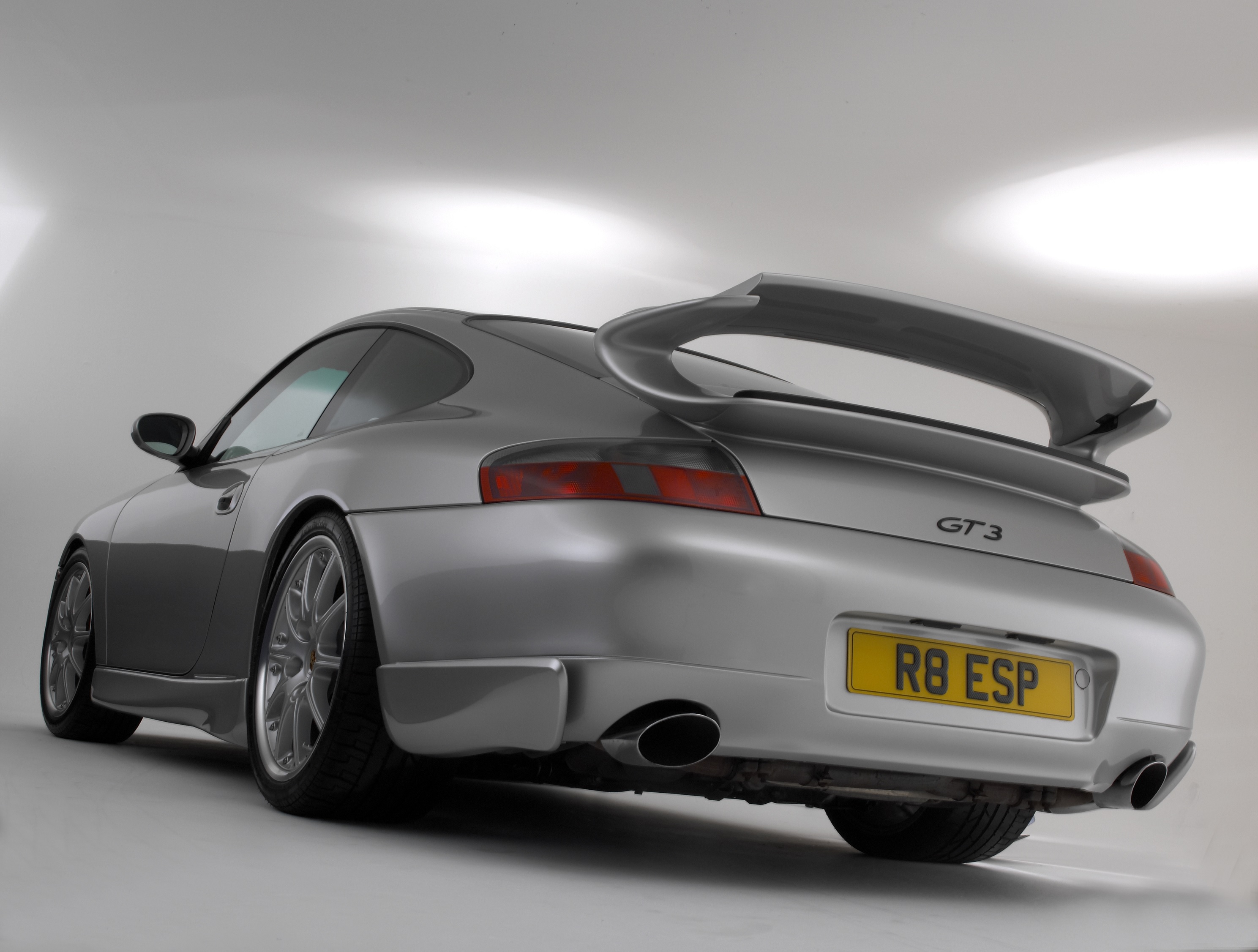 The rear 3/4 view of a silver 2000 996.1 Porsche 911 GT3 in a white studio