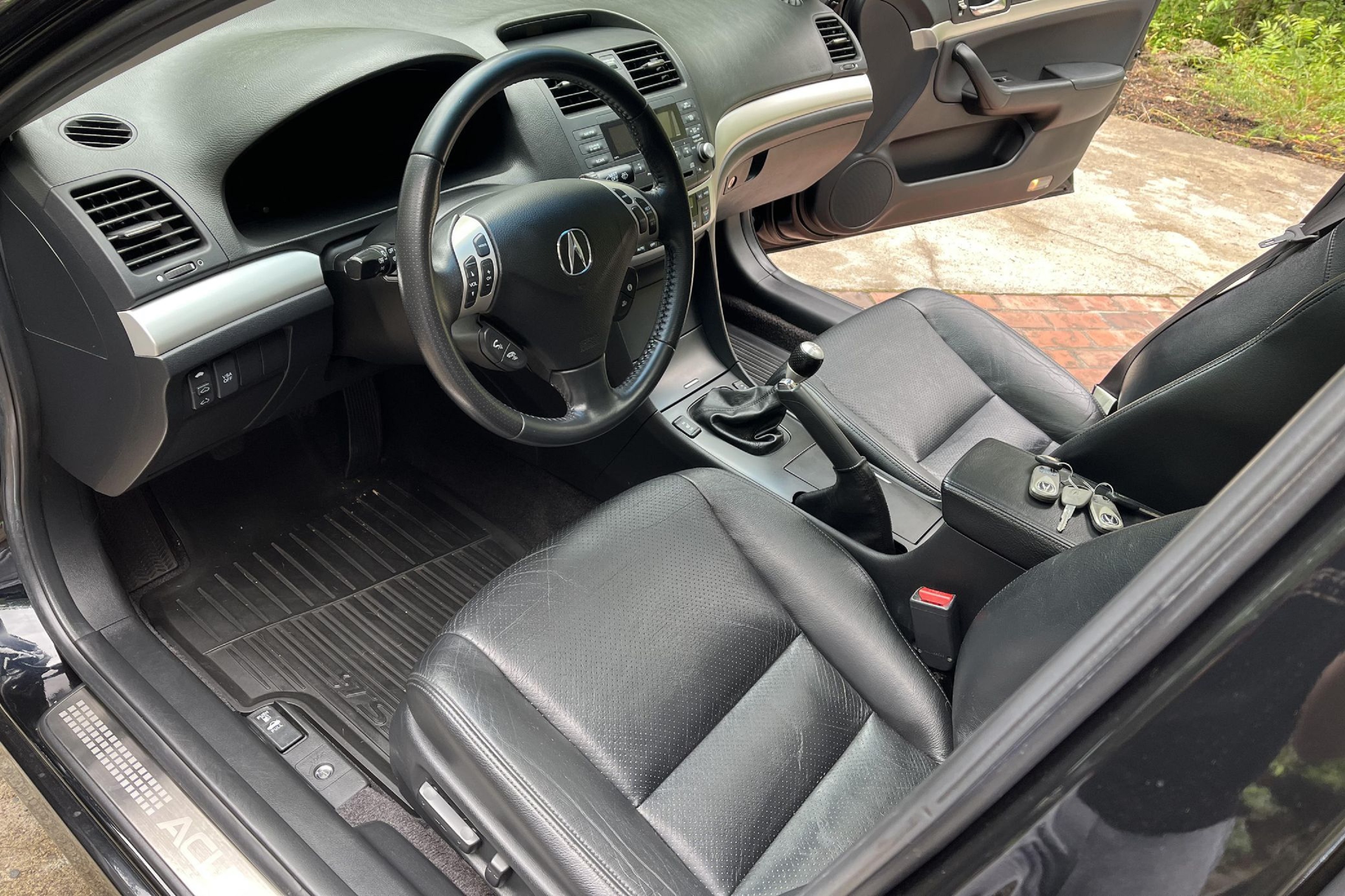 The black-leather front seats and black dashboard of a manual 2008 Acura TSX