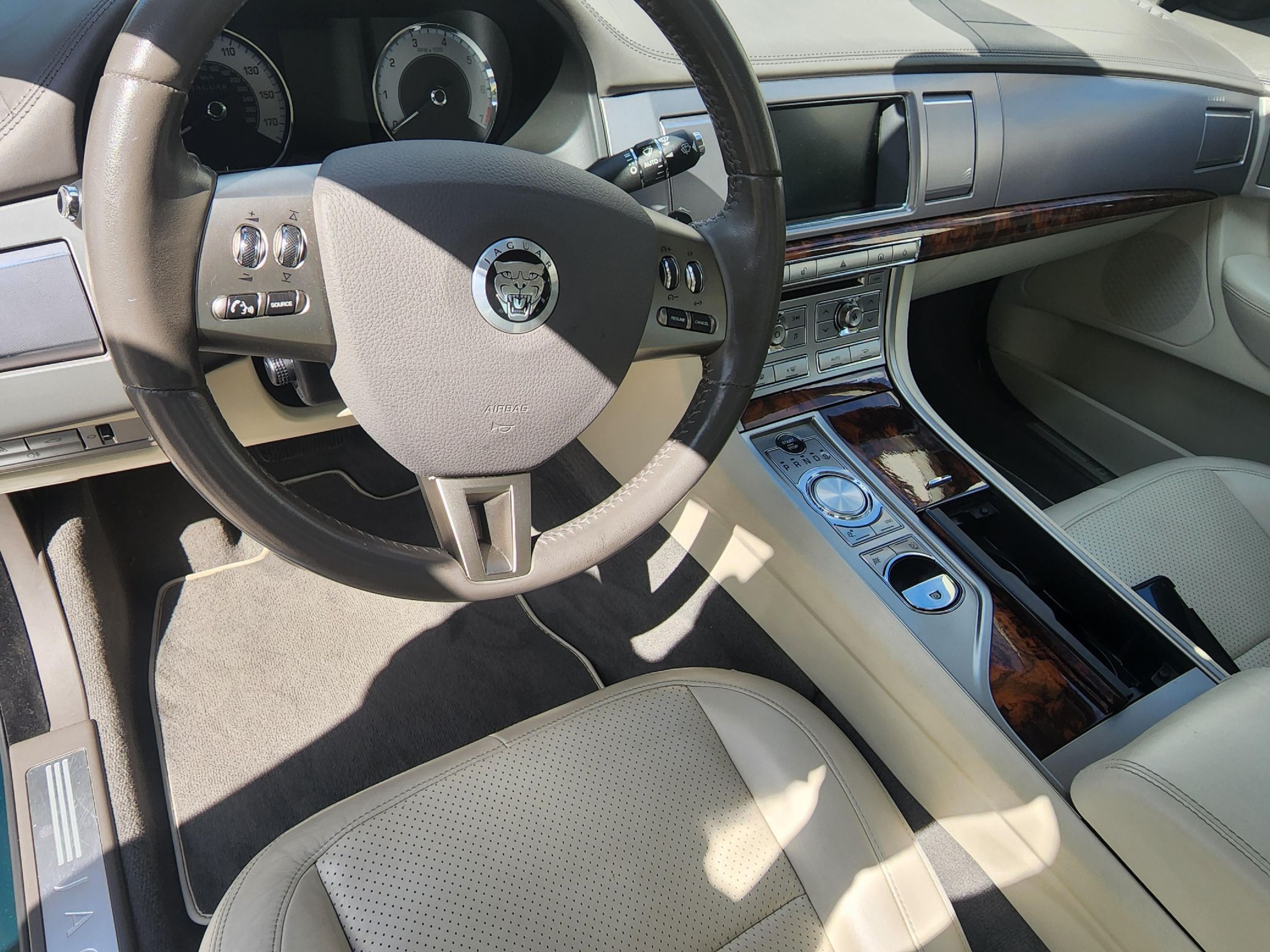 The tan-leather front seats and leather-upholstered dashboard of a used 2009 Jaguar XF Supercharged