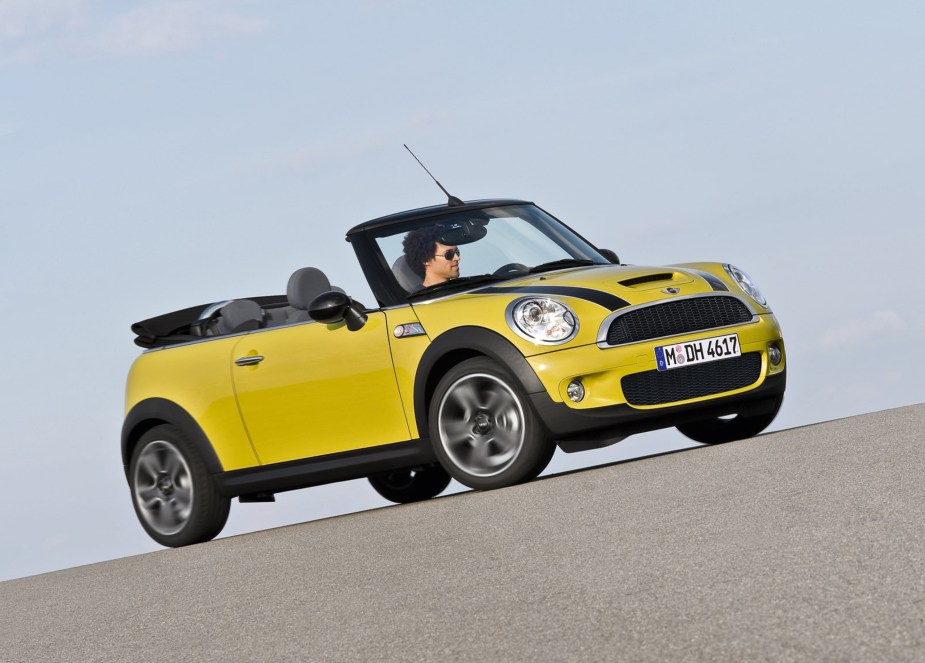 A yellow-with-black-stripes 2009 R57 Mini Cooper S Convertible with its roof down