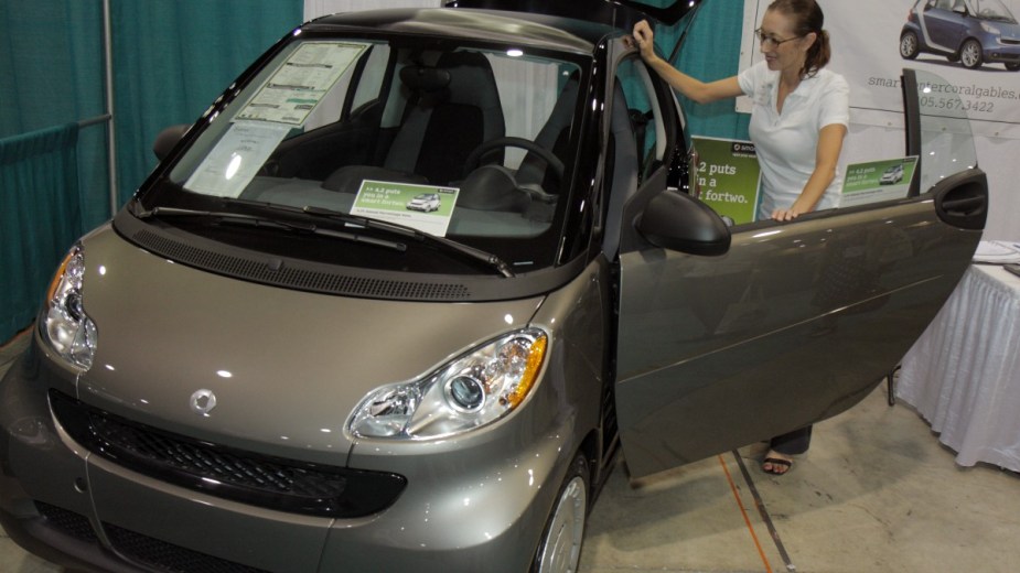 a woman looking at a 2009 smart fortwo, a great subcompact car that costs pennies
