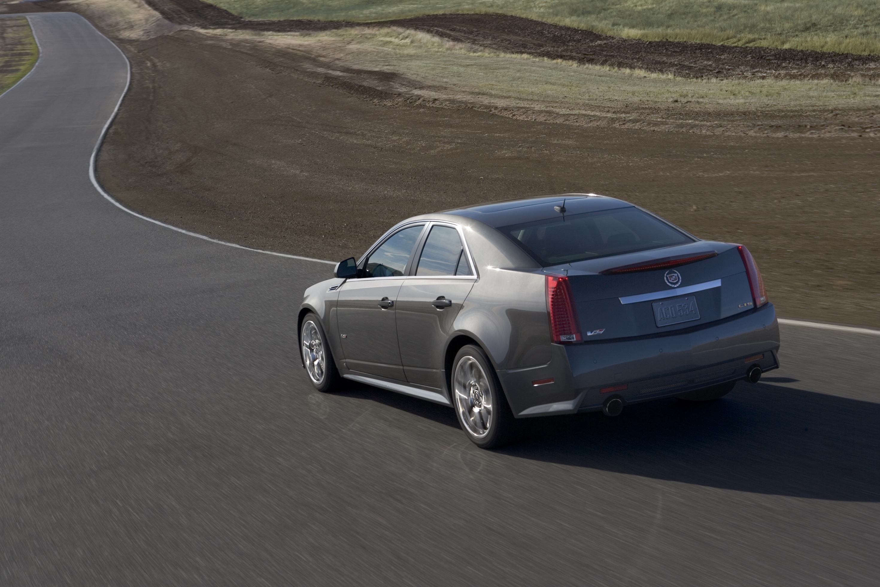 The rear 3/4 view of a gray 2011 Cadillac CTS-V Sedan driving around a track