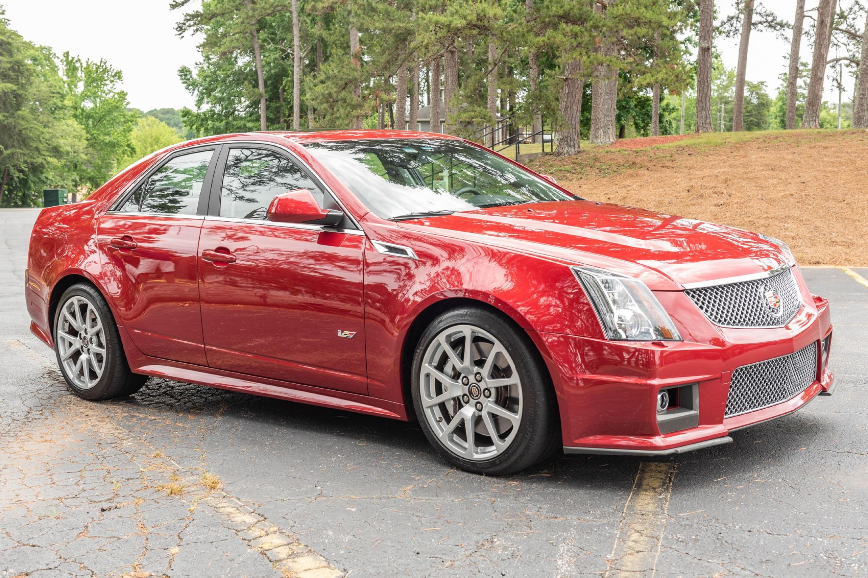 A red 2011 Cadillac CTS-V Sedan in a woods parking lot