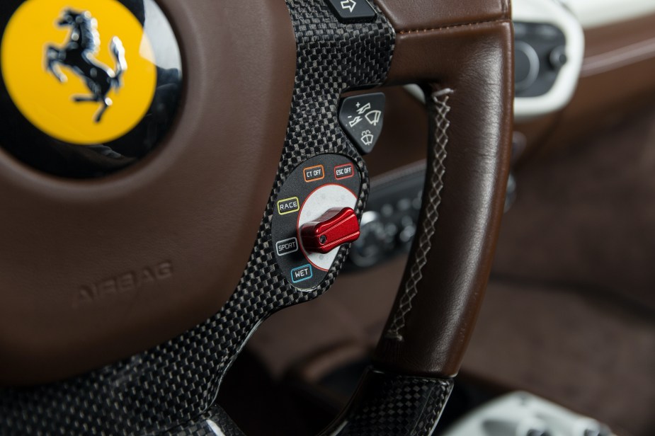 A 2012 Ferrari 458 Spider's brown steering wheel with its red driving mode switch with an Electronic Stability Control Off setting