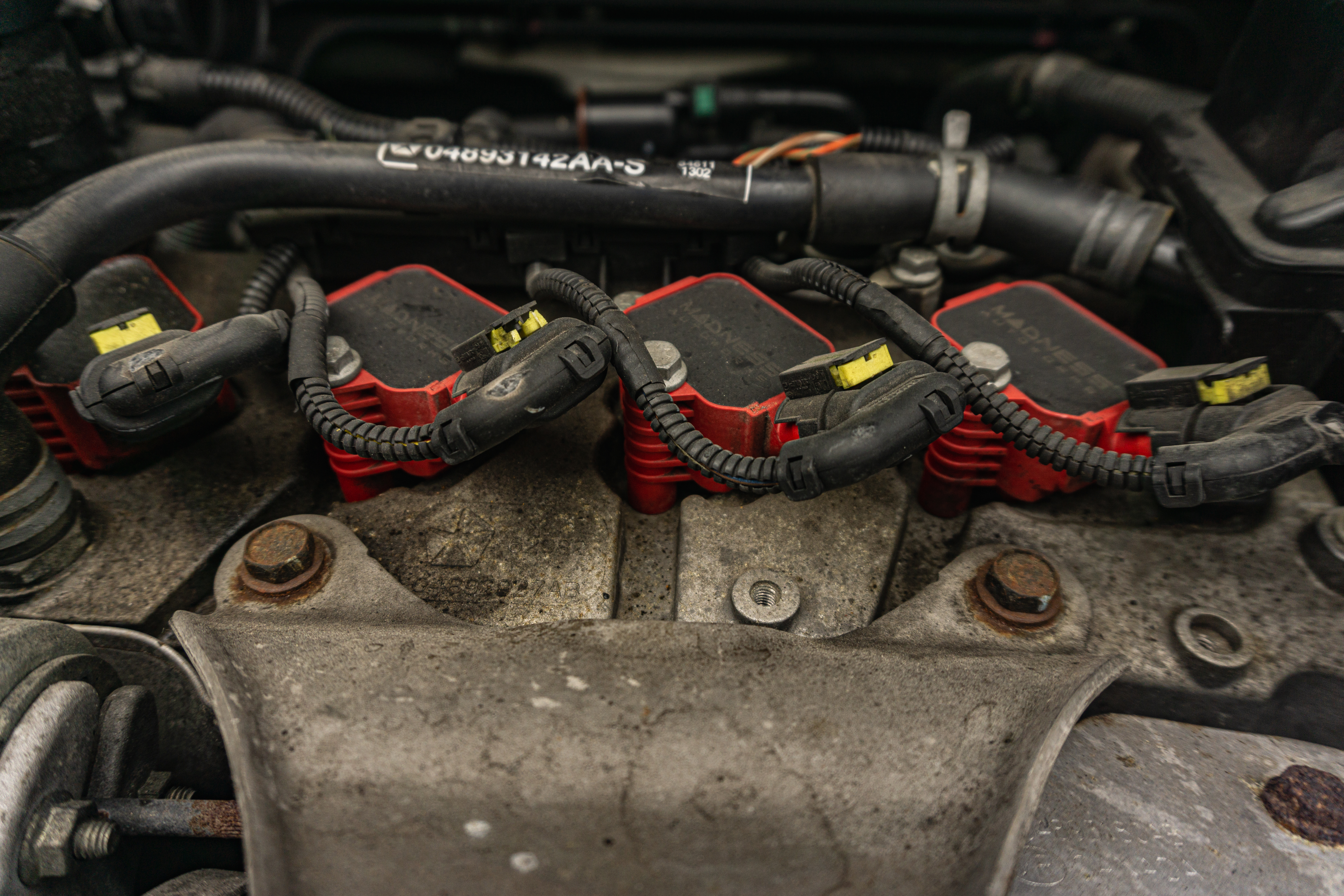 A close-up view of the ignition coils, as well as their bolts and wiring harnesses, in a 2013 Fiat 500 Abarth