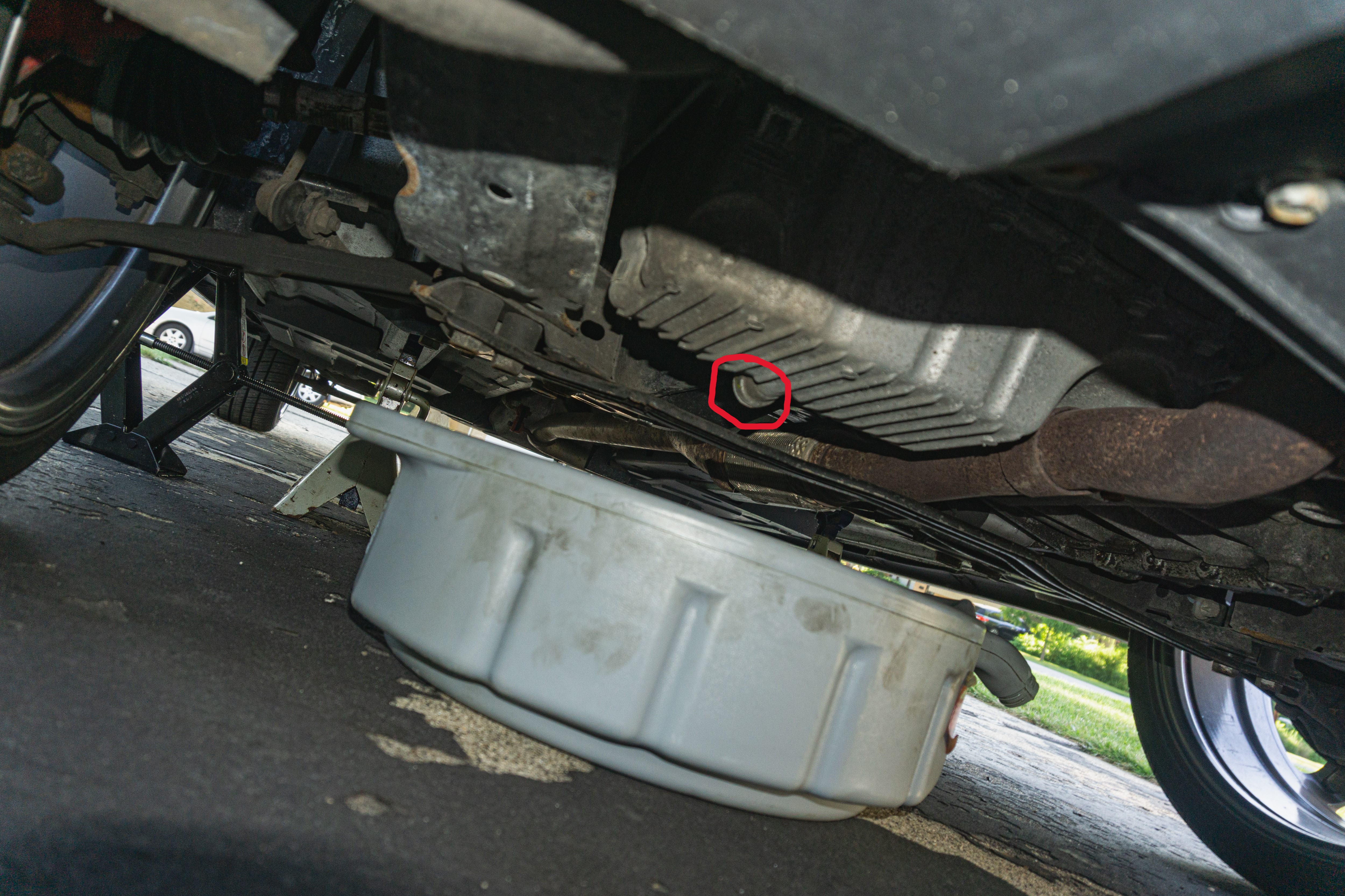 The oil pan in a 2013 Fiat 500 Abarth with the drain plug circled in red