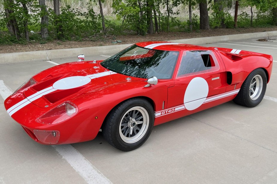 A red-with-white-stripes 2016 Race Car Replicas Ford GT40 Mk1 in a parking lot