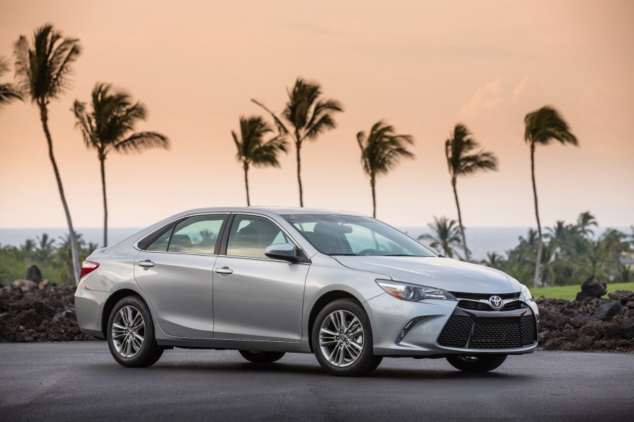 A silver 2017 Toyota Camry used midsize sedan parked in front of palm trees