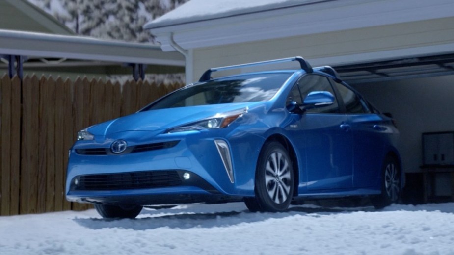 a blue 2020 toyota prius tackling a snowy driveway thanks to the available all wheel drive system