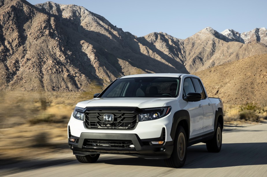 Advertising photo of the front of a compact Honda Ridgline pickup truck as it drives through the mountains.