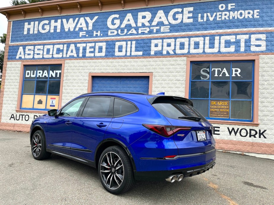 A rear-angled view of the 2022 Acura MDX in front of a car museum wall.