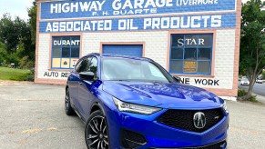 A front-angled view of the 2022 Acura MDX Type S in front of a car museum wall.