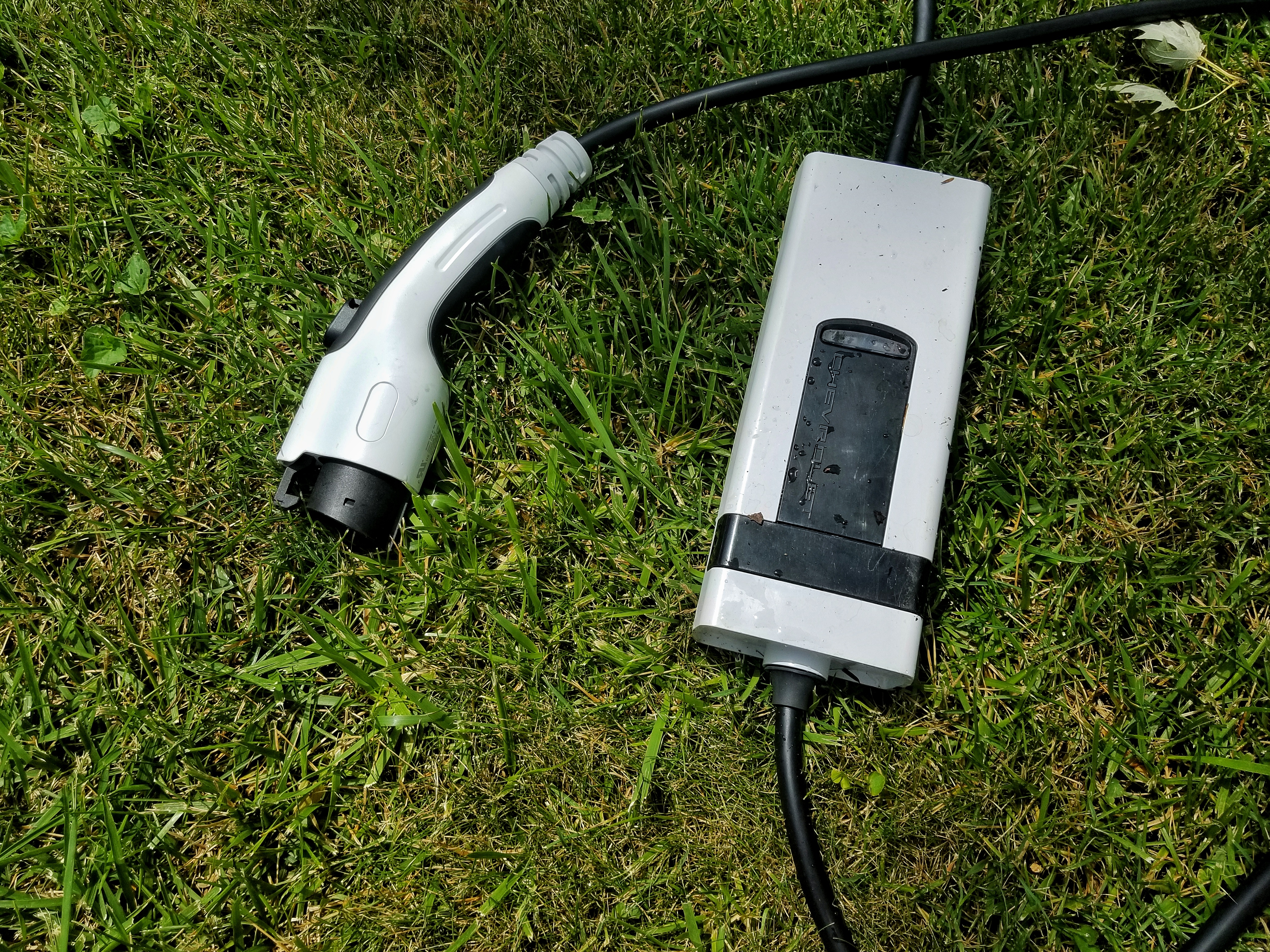 A white 2022 Chevrolet Bolt EUV charge cord after a thunderstorm on a lawn