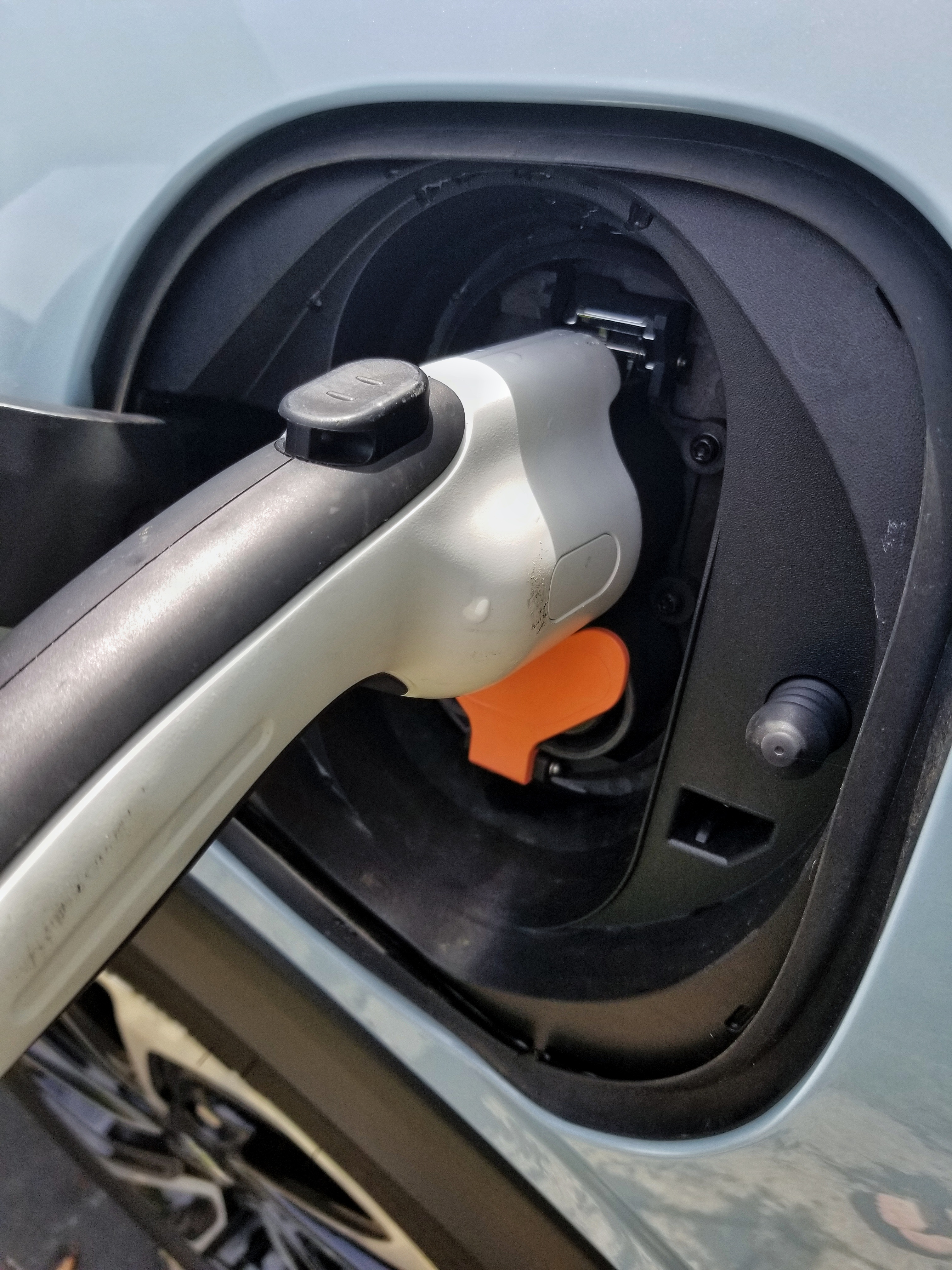 The charging port of a light-blue 2022 Chevrolet Bolt EUV after a thunderstorm with the charge cable plugged in