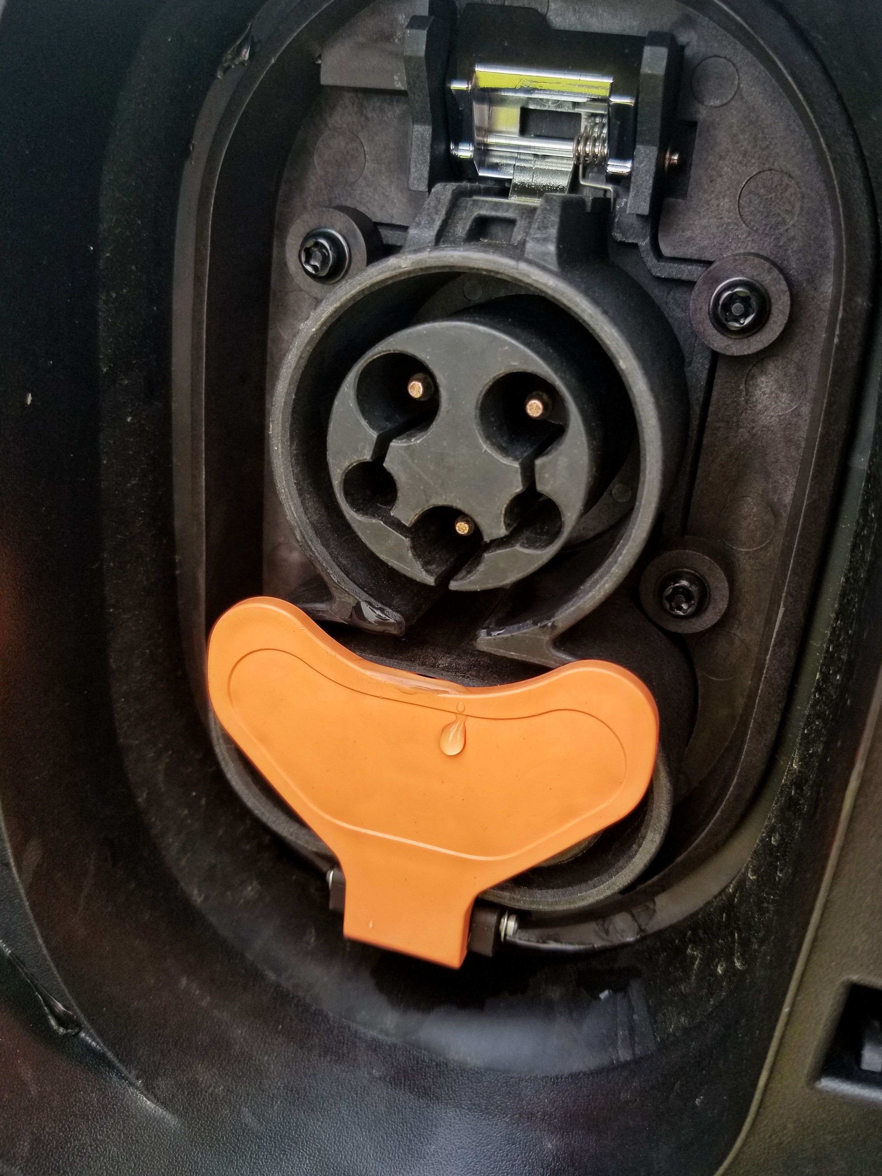 The open black-and-orange charging port of a 2022 Chevrolet Bolt EUV after a thunderstorm