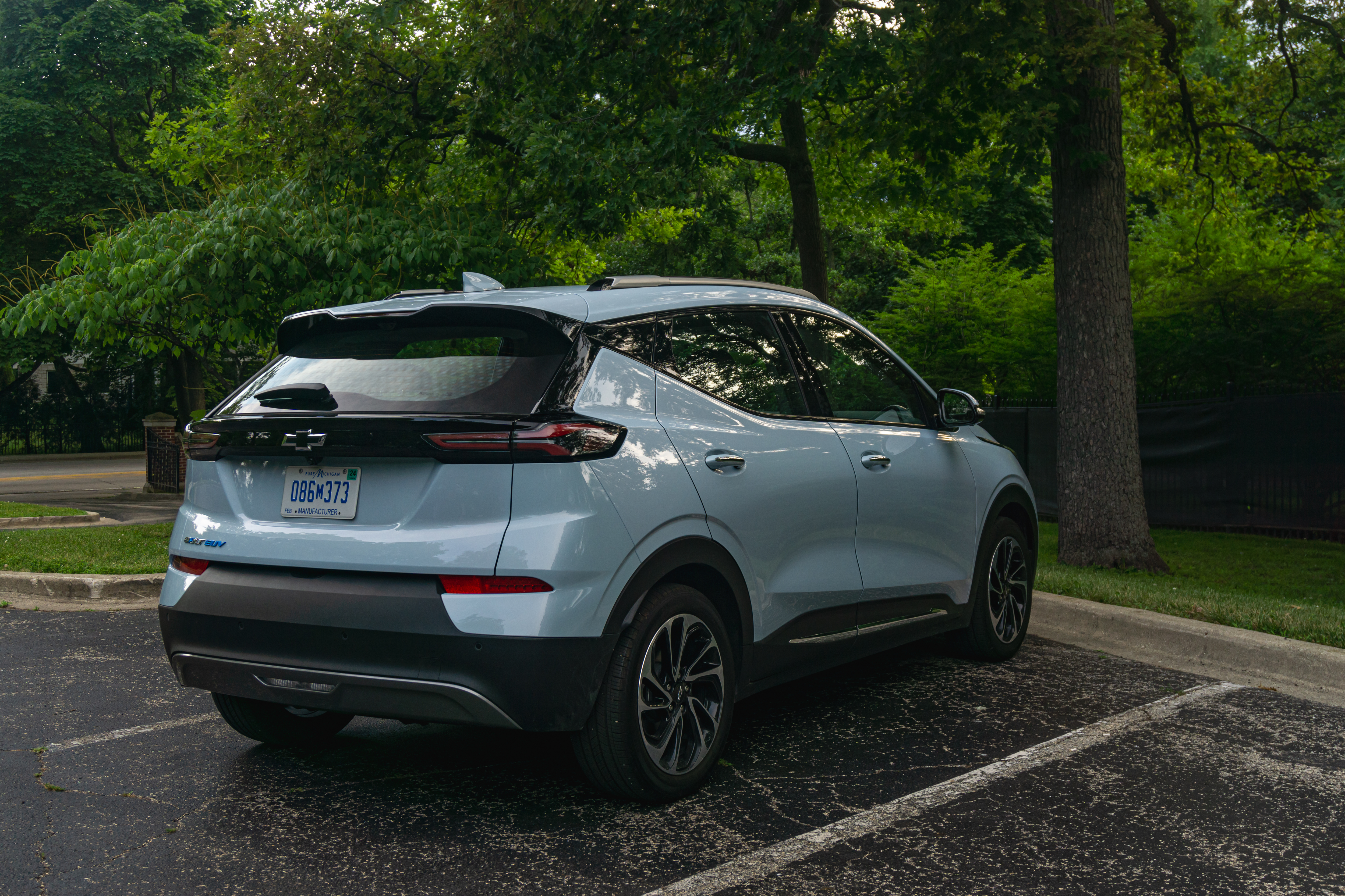 The rear 3/4 view of a light-blue 2022 Chevrolet Bolt EUV Premier in a forest parking lot