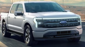 A gray 2022 Ford F-150 lightning is driving on the road.