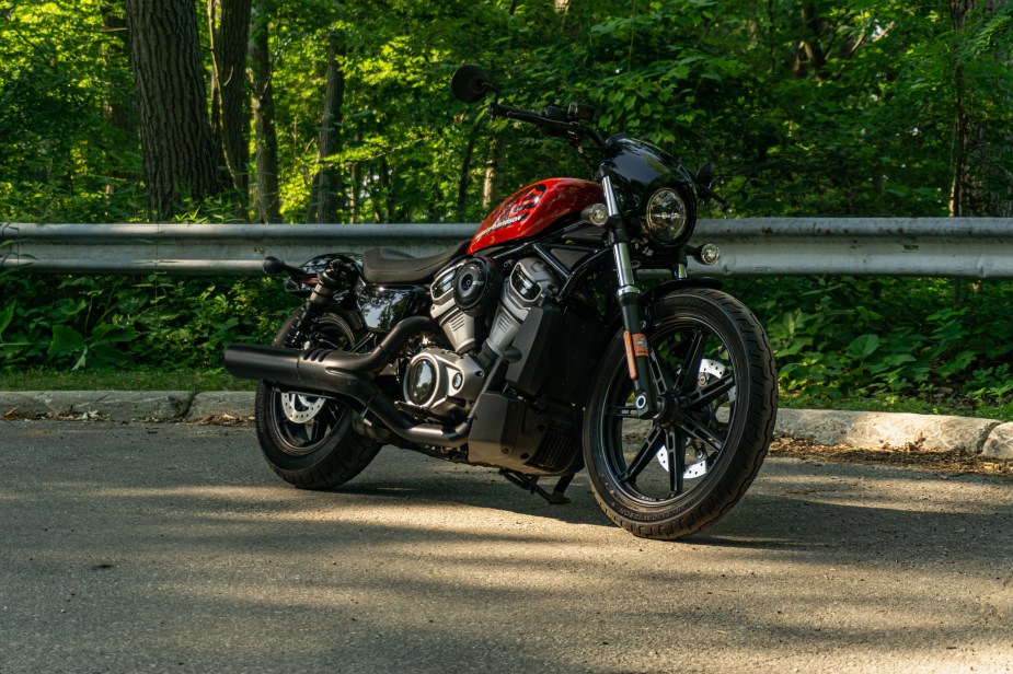 The front 3/4 view of a red-and-black 2022 Harley-Davidson Nightster on a forest road